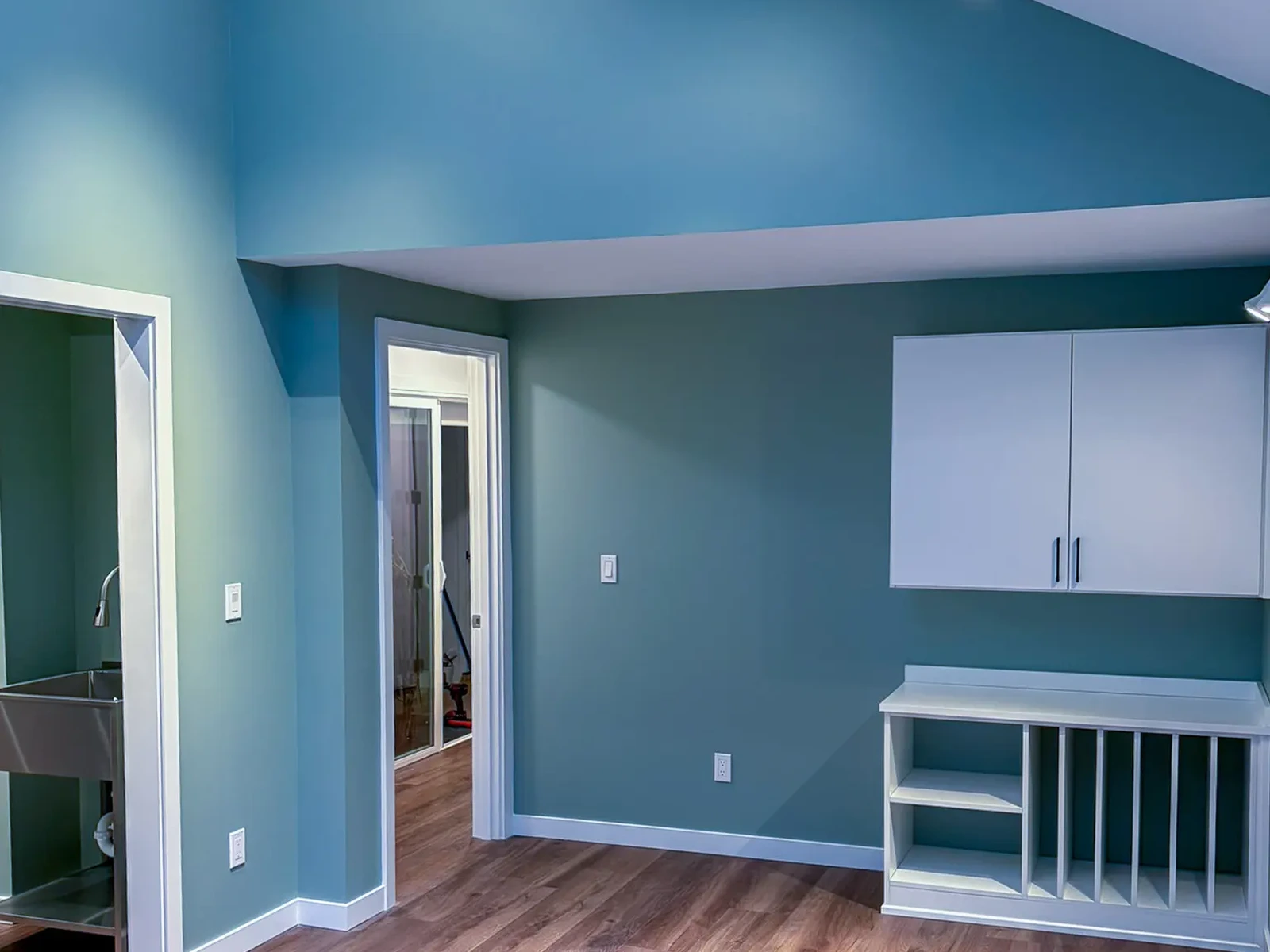 Completed mother-in-law apartment addition in Kirkland, WA, showing the vaulted ceiling, teal accent wall, wood-look flooring, and built-in cabinetry.
