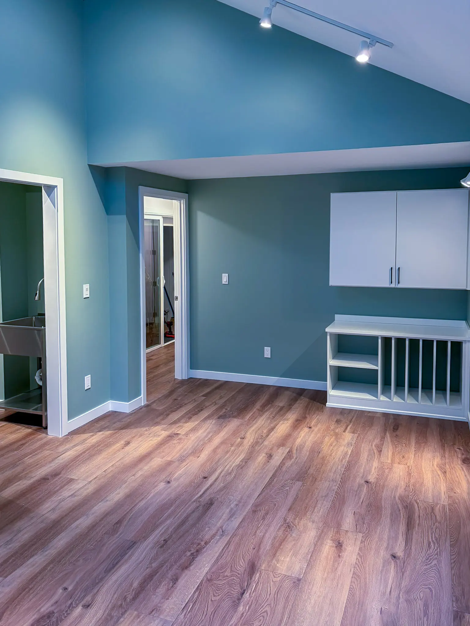 Open room with teal accent wall, wood-look flooring, and built-in white cabinetry in the completed Kirkland, WA mother-in-law apartment addition.