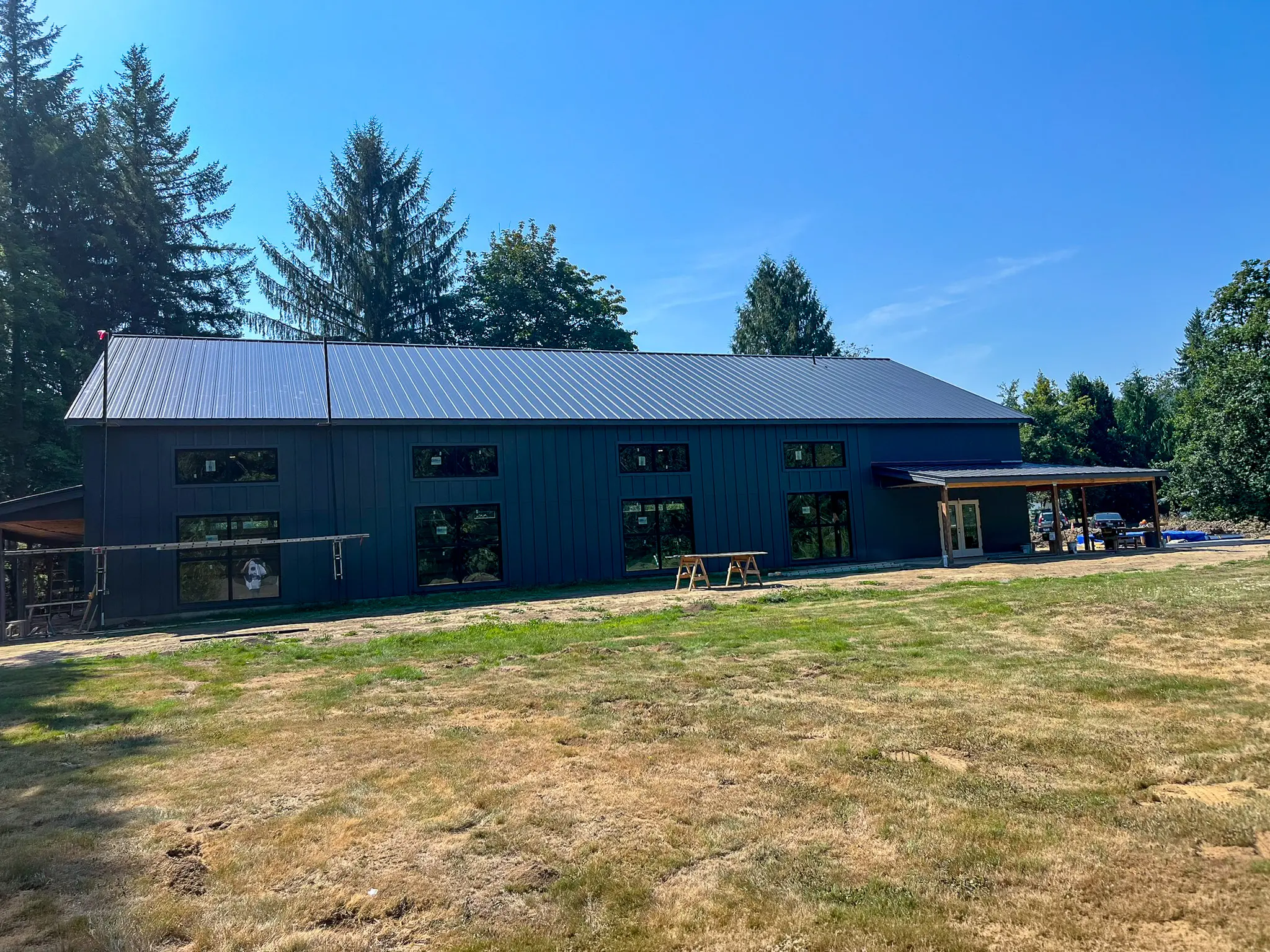 Long exterior view of the completed detached shop's dark board-and-batten siding and standing-seam metal roof on a Fall City, WA property.