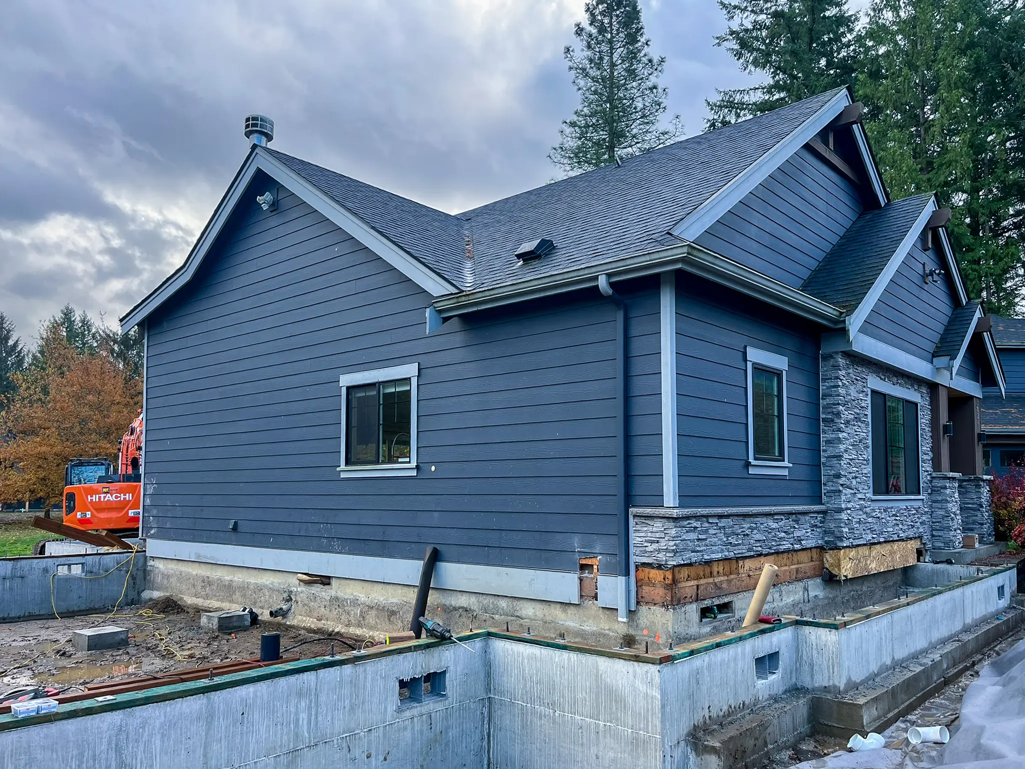 Exterior of the remodeled home in Fall City, WA, showing blue siding and a stone accent base as part of a whole-home remodel and addition.