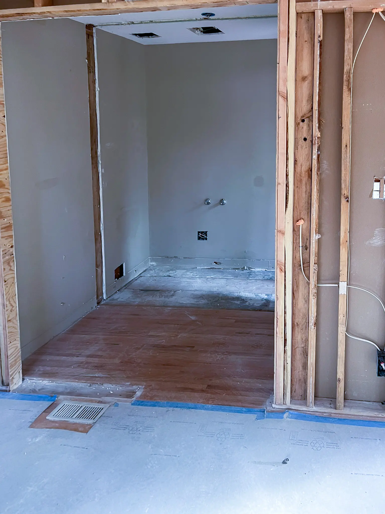 Interior room with drywall installed and hardwood flooring partially laid during construction of a new custom home in Redmond, WA.