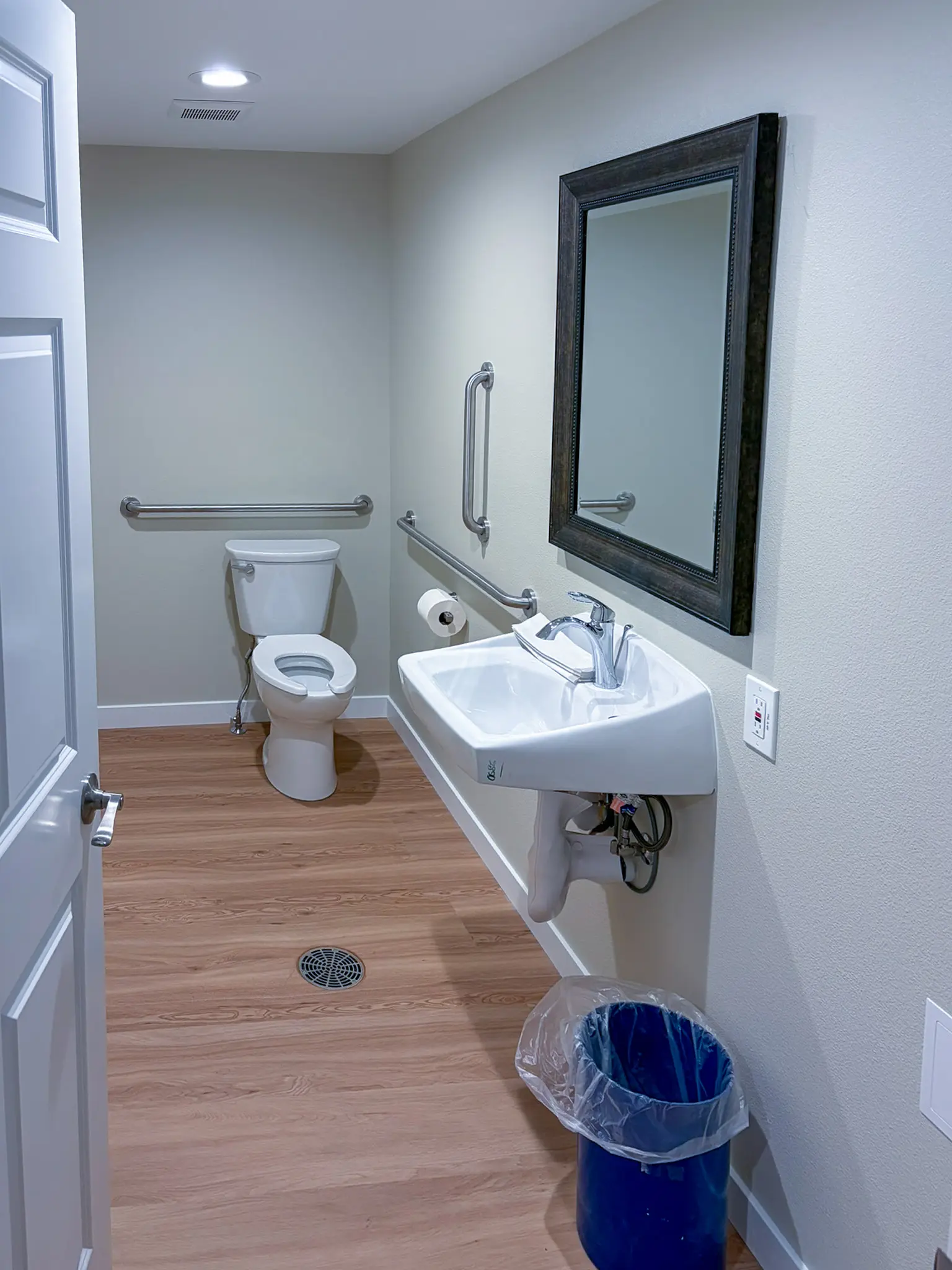 Bathroom with grab bars and a wall-mounted sink in the remodeled Redmond, WA daycare.