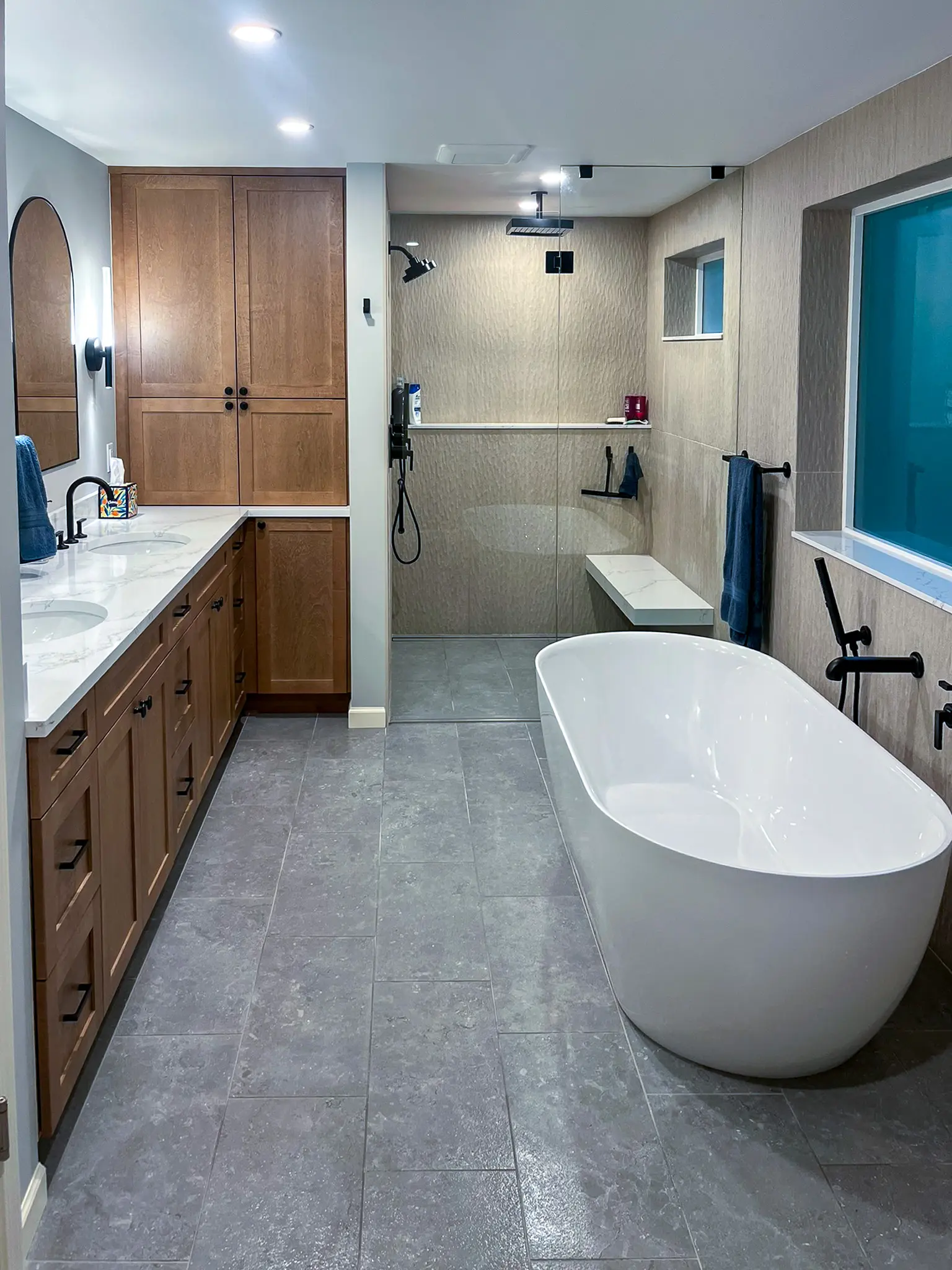 Primary bathroom with a freestanding soaking tub, curbless tiled shower, and wood double vanity in a Bellevue, WA home.