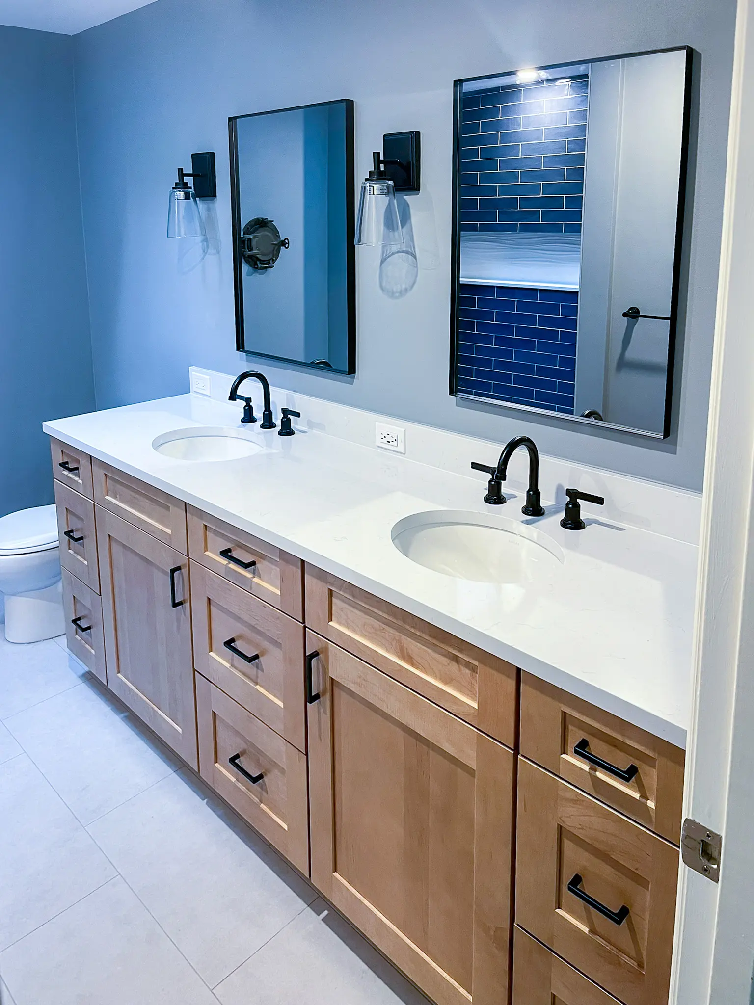Bathroom with a wood double vanity, black fixtures, and blue walls in a Bellevue, WA home.