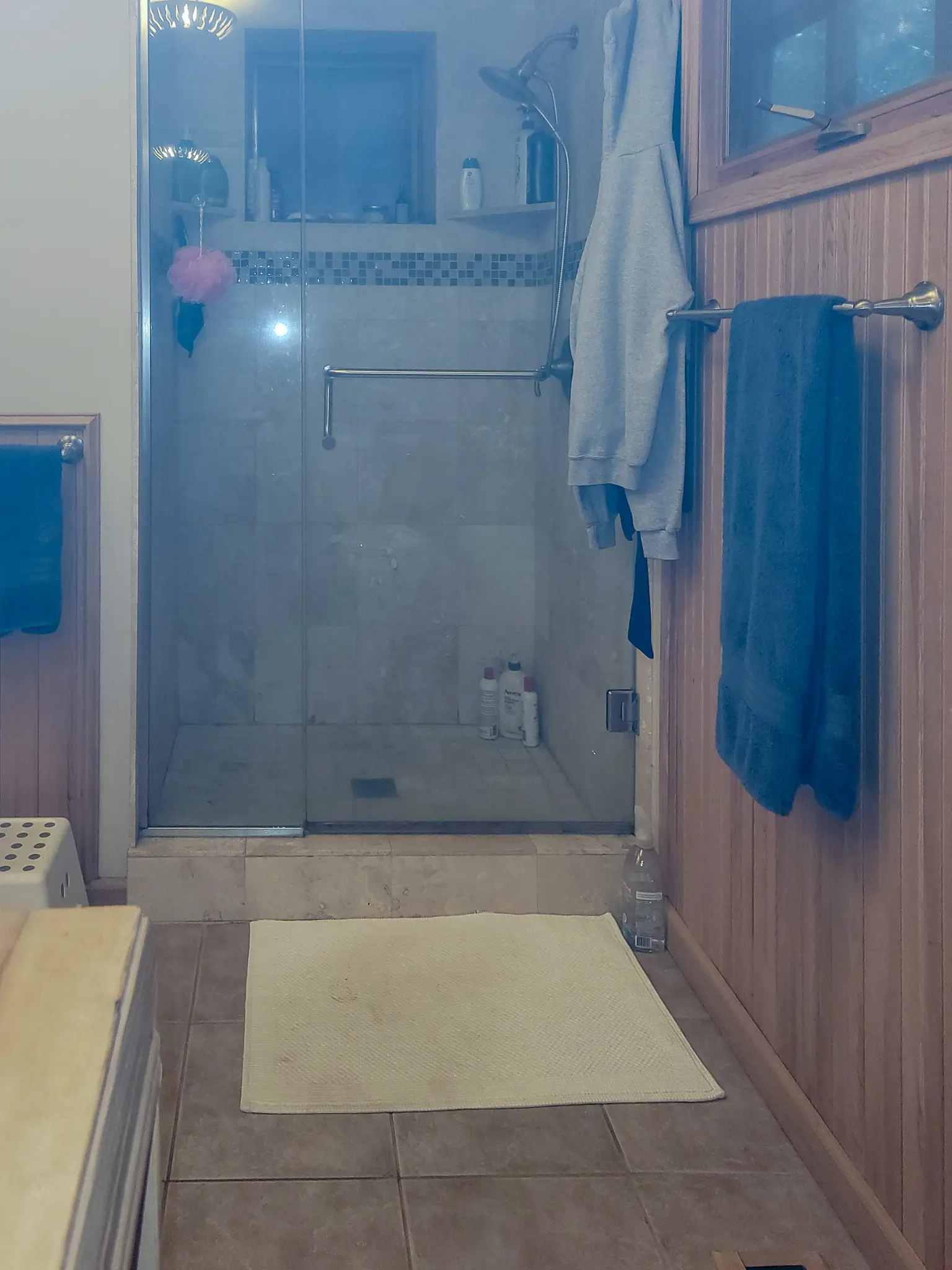 Existing primary bathroom with a glass-enclosed tile shower and wood paneling in a Bellevue, WA home before a bathroom remodel.