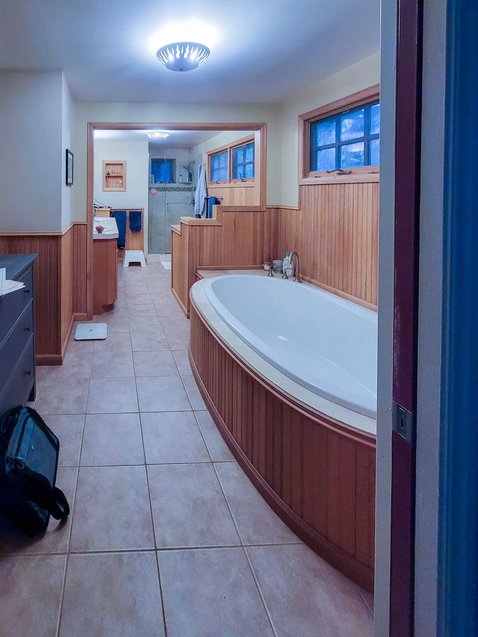 Existing primary bathroom with a wood-surround soaking tub and tile flooring in a Bellevue, WA home before a bathroom remodel.