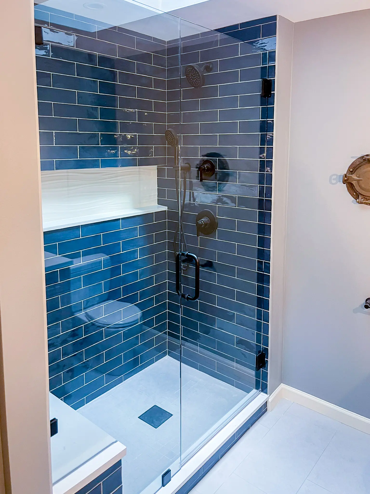 Glass-enclosed shower with blue subway tile in a Bellevue, WA home.