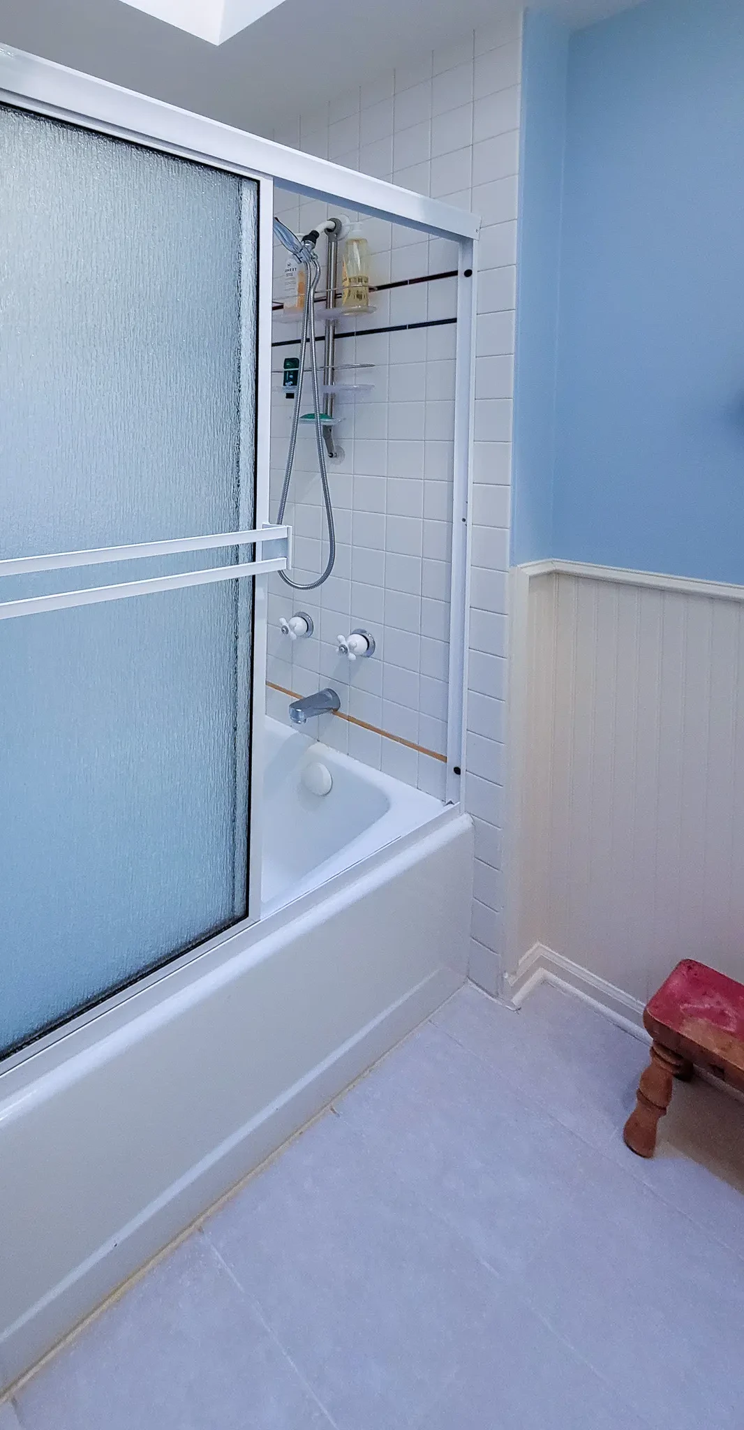 Existing tub-shower combo with sliding glass doors and blue tile in a Bellevue, WA home before a bathroom remodel.