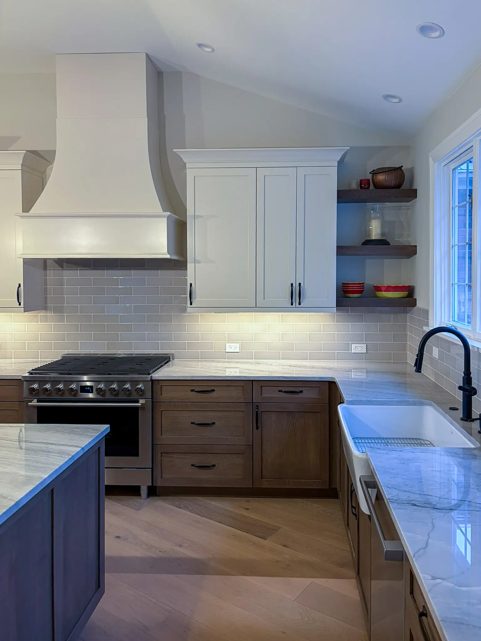 Kitchen with a range hood, subway tile backsplash, and farmhouse sink after a whole-home remodel in Sammamish, WA.