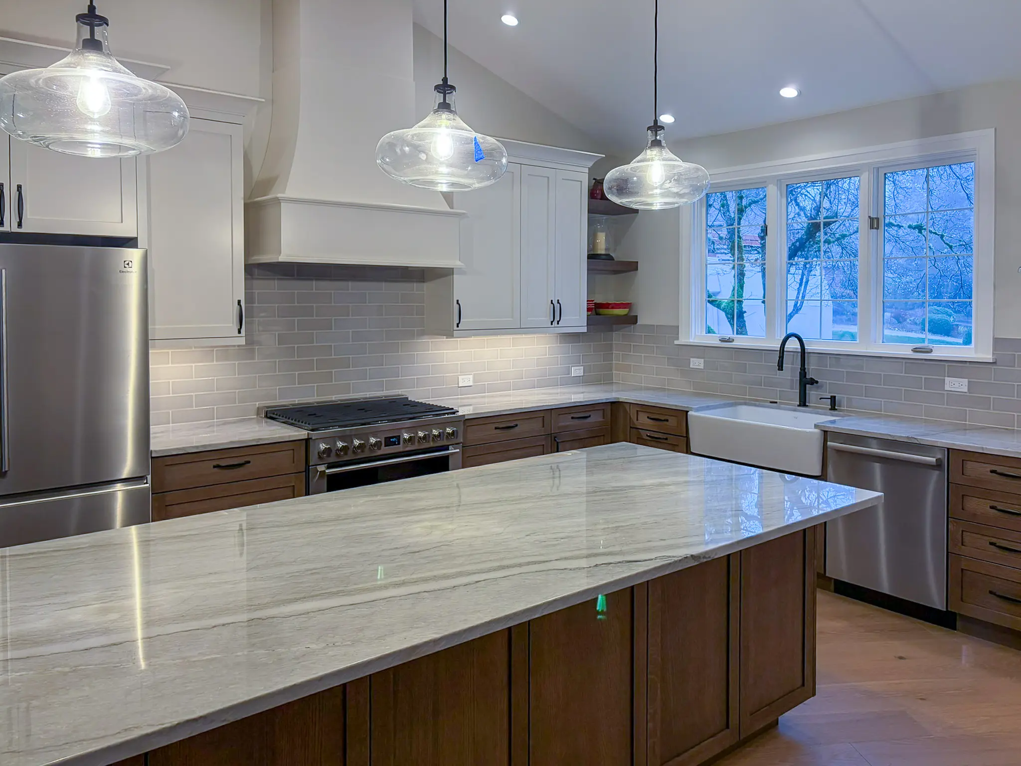Kitchen island with a waterfall-edge countertop, pendant lighting, and stainless appliances after a whole-home remodel in Sammamish, WA.