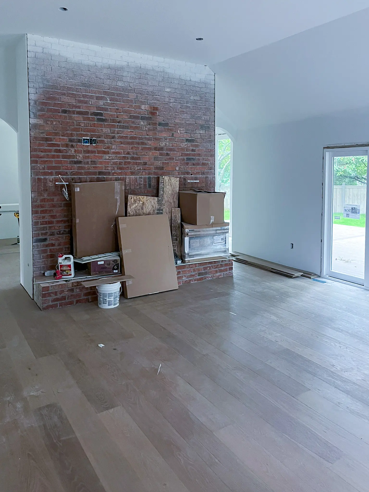 Interior room with an exposed brick wall, wood flooring, and construction materials in a Sammamish, WA home before a whole-home remodel.