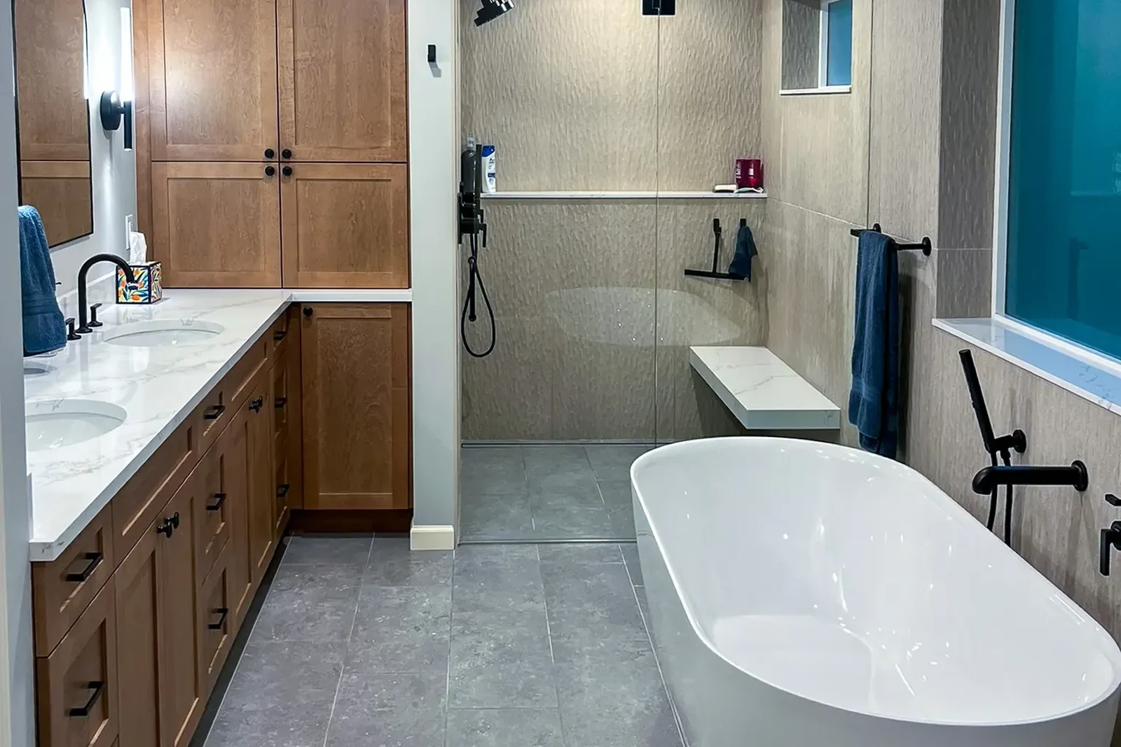 Primary bathroom in a Bellevue, WA home, with a freestanding soaking tub, curbless tiled shower, and wood vanity.