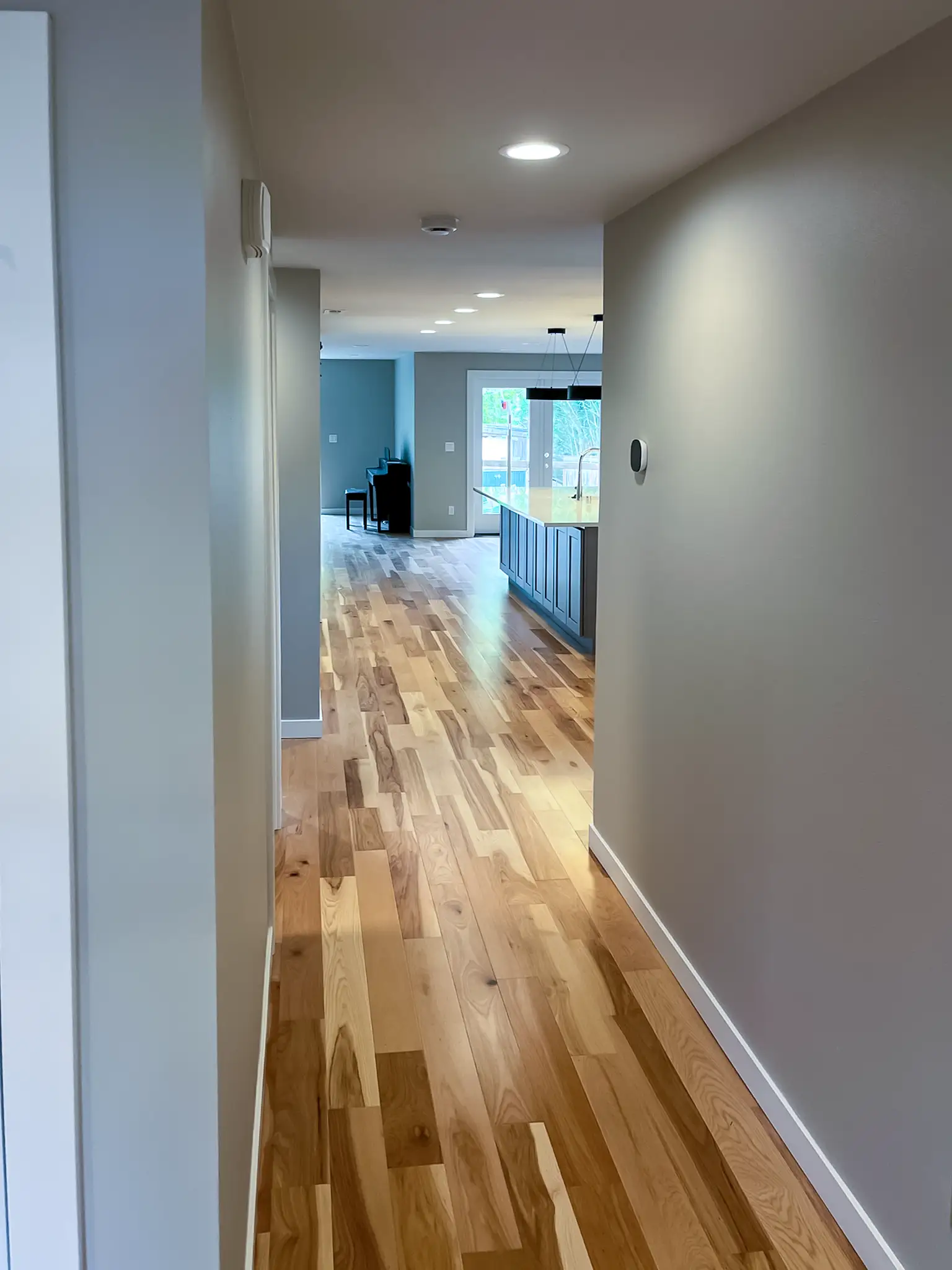 Remodeled entry hallway with new closet doors and wood-look flooring in a Kirkland, WA rambler.
