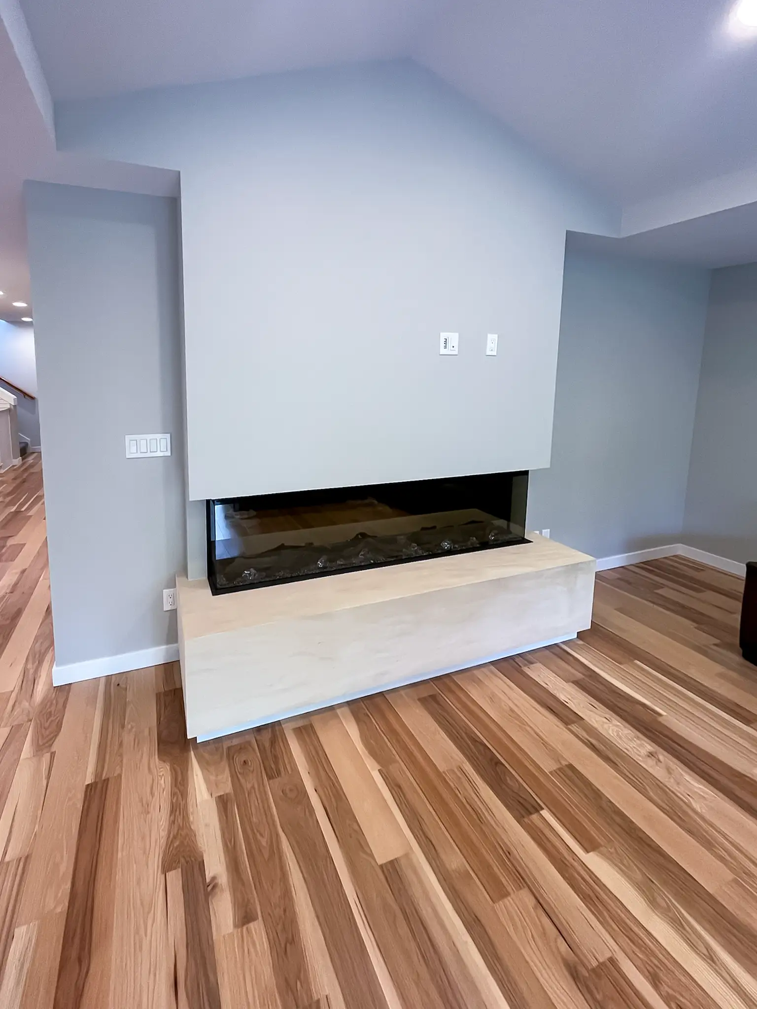 Linear fireplace built into a floating stone-look surround in a remodeled Kirkland, WA living room.