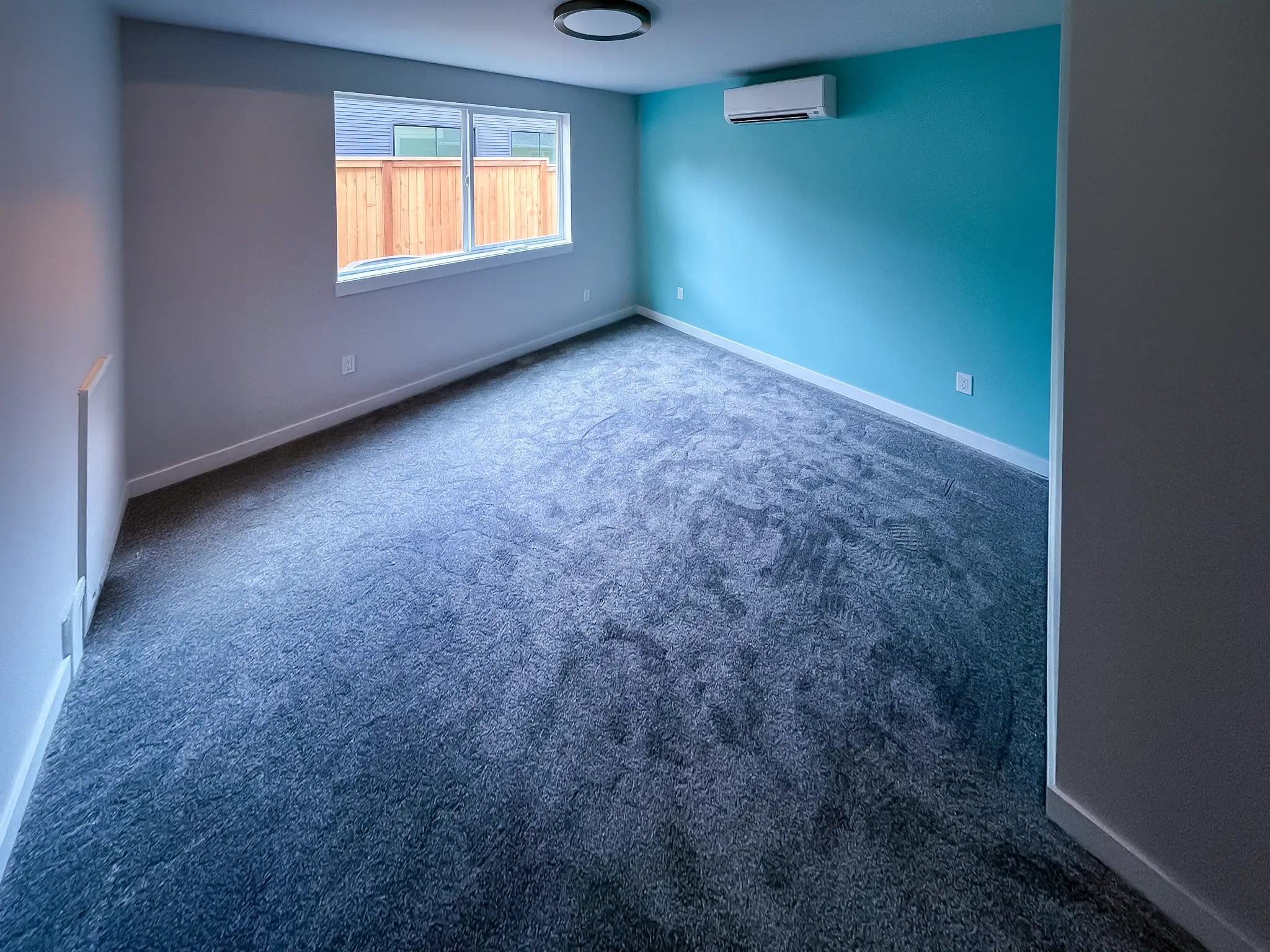 Remodeled bedroom with new carpet, an accent wall, and a ductless mini-split unit in a Kirkland, WA rambler.