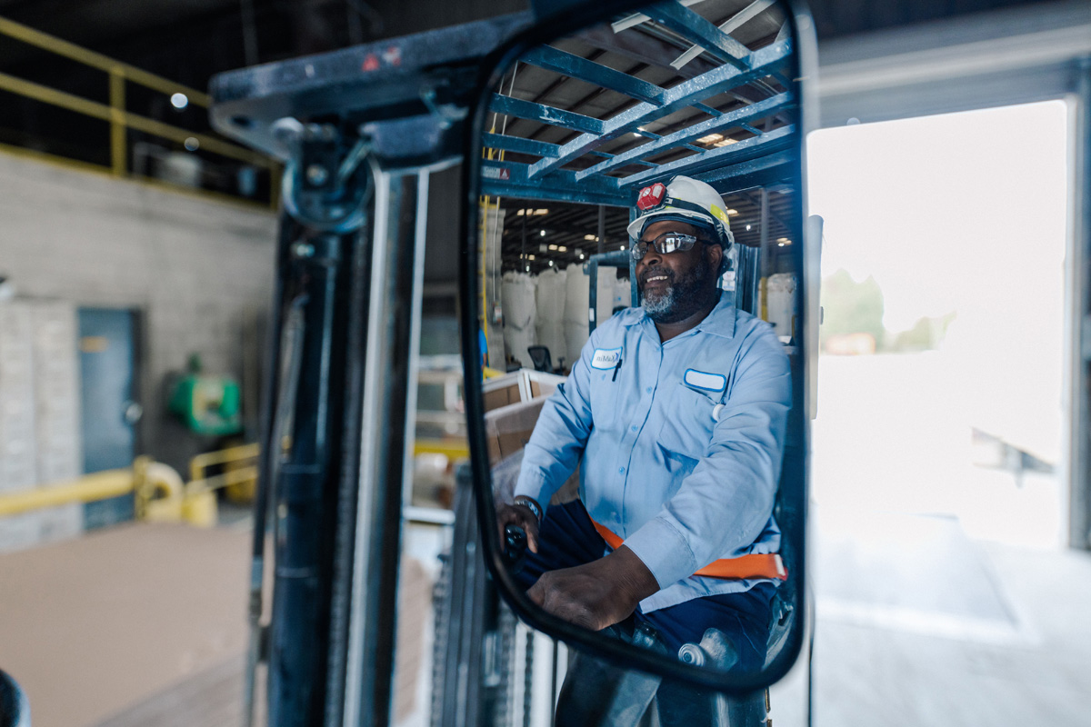 kamin employee operating equipment in safety hard hat at kaolin clay manufacturing plant