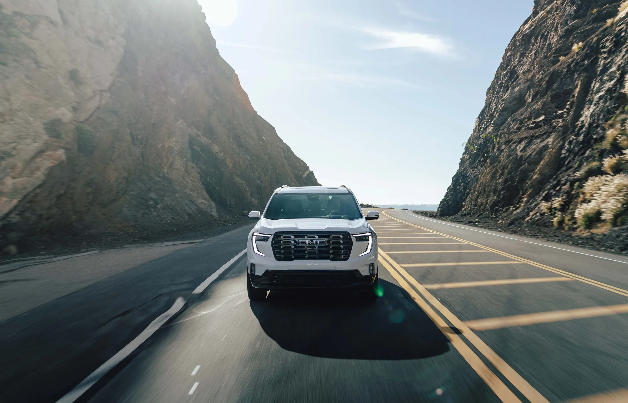 White SUV driving a canyon road