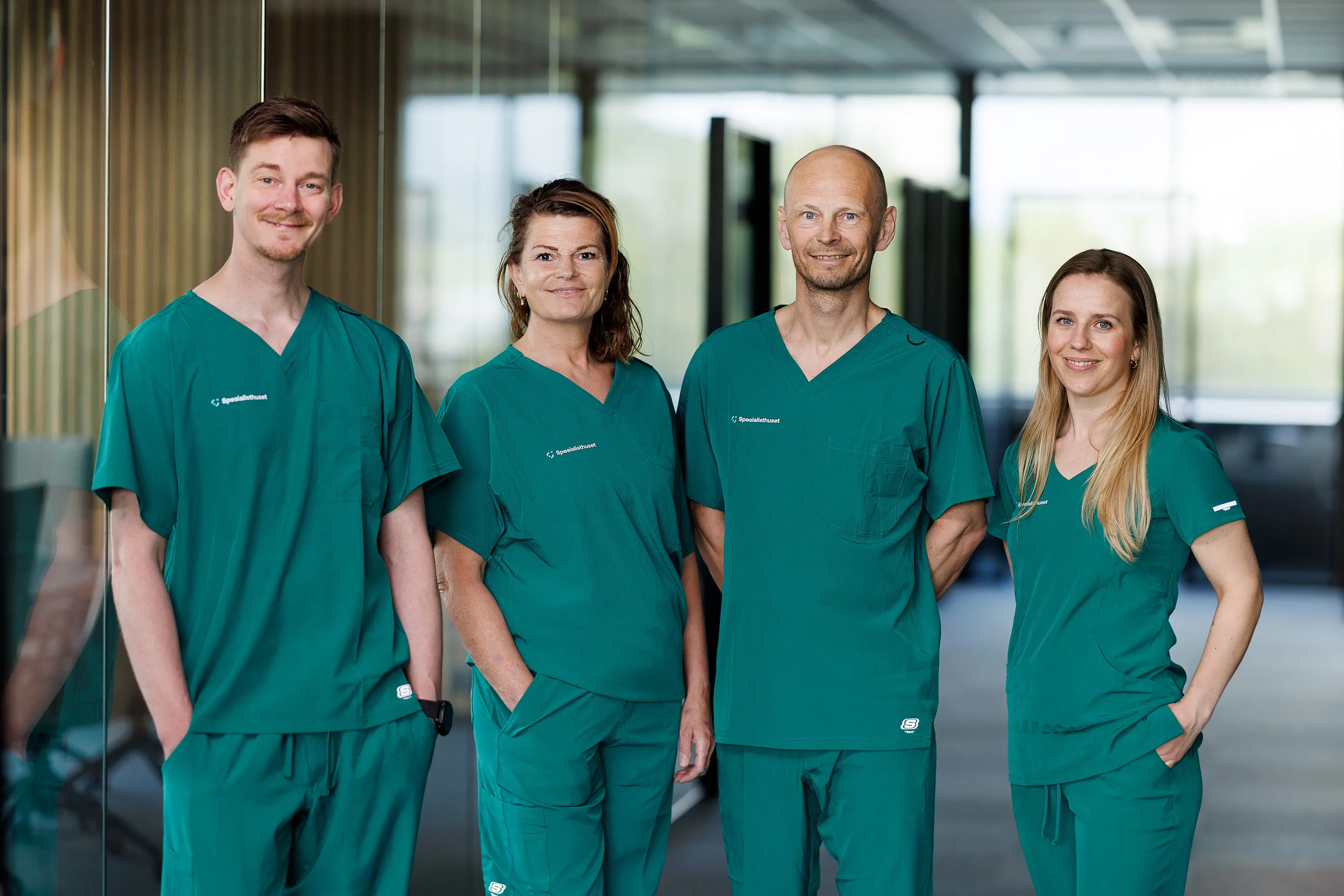 Bilde av fire helsearbeidere iført Spesialisthusets sykehusuniform (scrubs).