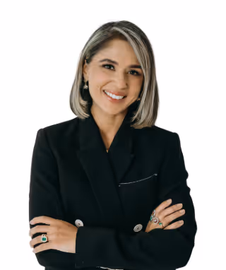 Smiling woman with shoulder-length gray hair wearing a black blazer and colorful rings with arms crossed.