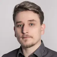 Porträt eines jungen Mannes im schwarzen Hemd vor neutralem, hellem Hintergrund.