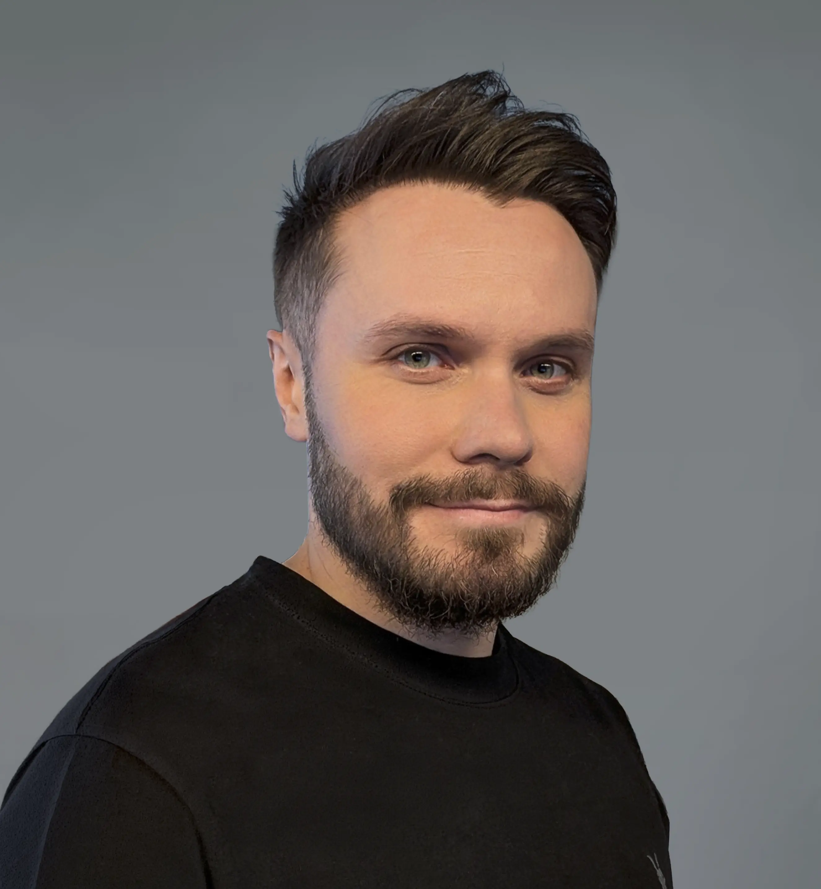 Porträt von Denis Schmidt, Gründer der dencraft werbeagentur, vor grauem Hintergrund in schwarzem Shirt.