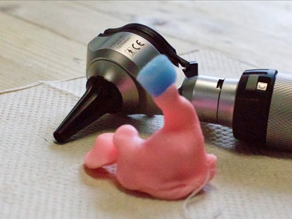 Custom Ear Impression sitting next to an otoscope.