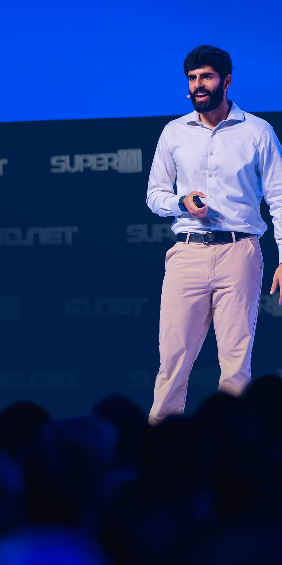 Dwarkesh Patel standing on a stage in front of a crowd, io.net stage SuperAI