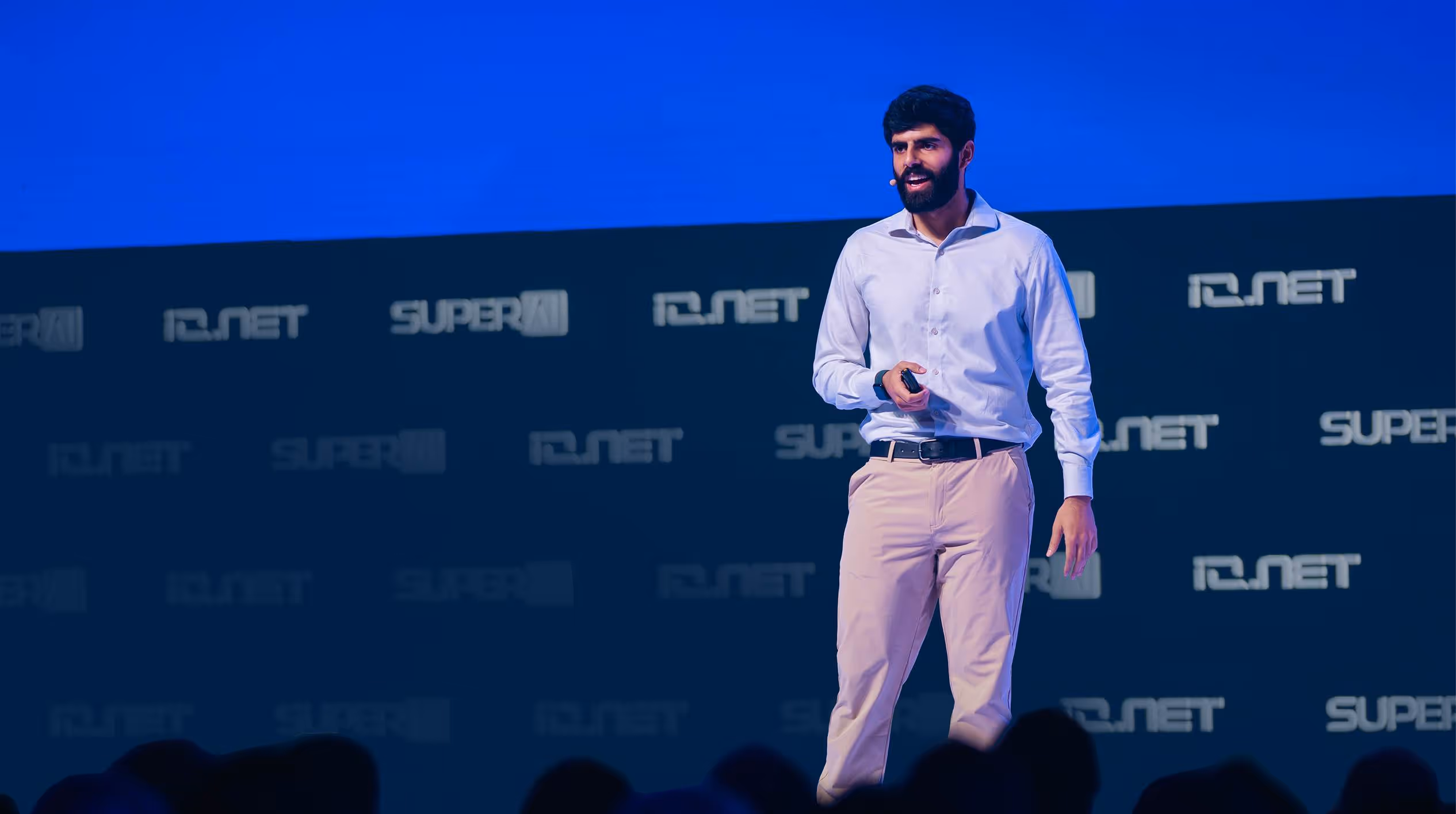 Dwarkesh Patel standing on a stage in front of a crowd, io.net stage SuperAI