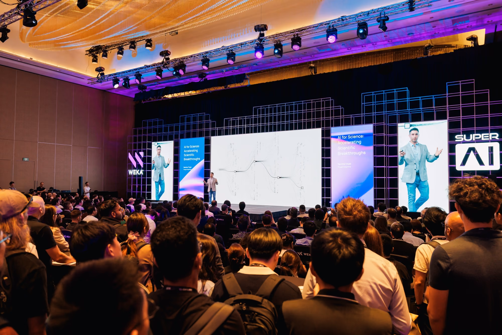 Speaker presenting "AI for Science: Accelerating Scientific Breakthroughs" on the WEKA stage at SuperAI 2026.
