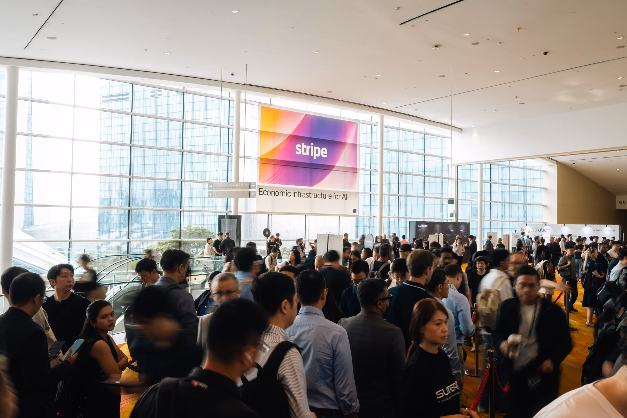 Crowd gathered beneath a Stripe "Economic infrastructure for AI" banner in the venue lobby.