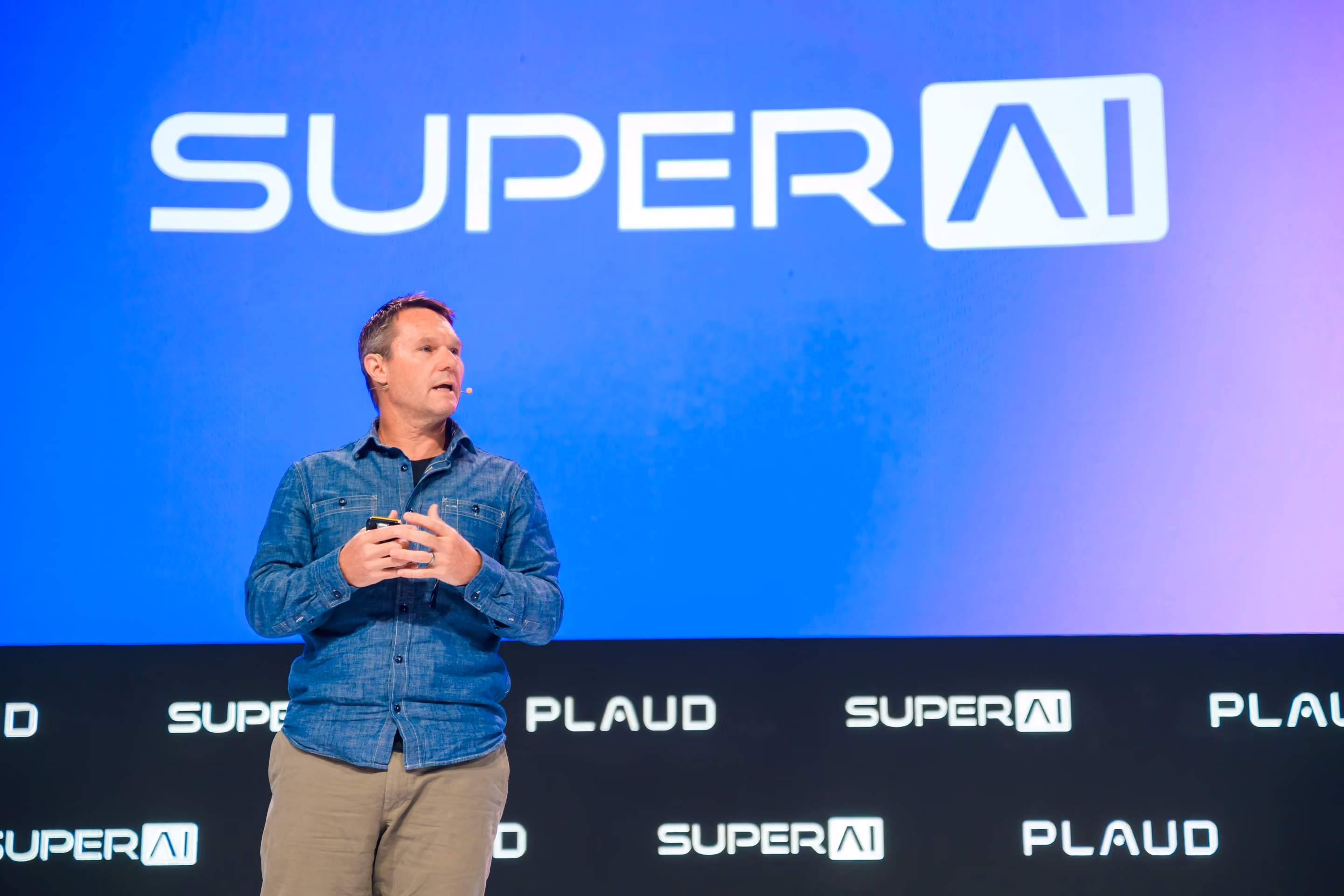Speaker addressing the audience on the SuperAI main stage in front of the SUPER AI logo backdrop.