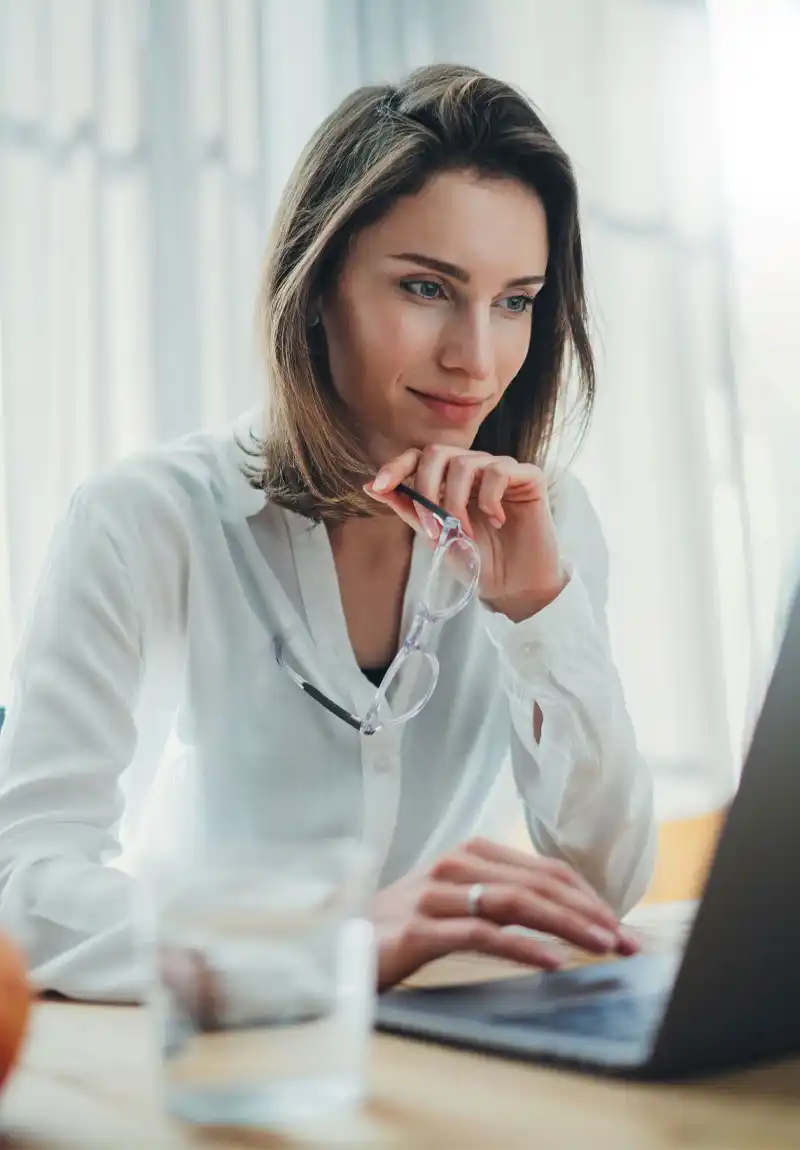 Woman in white blouse looking at laptop screen