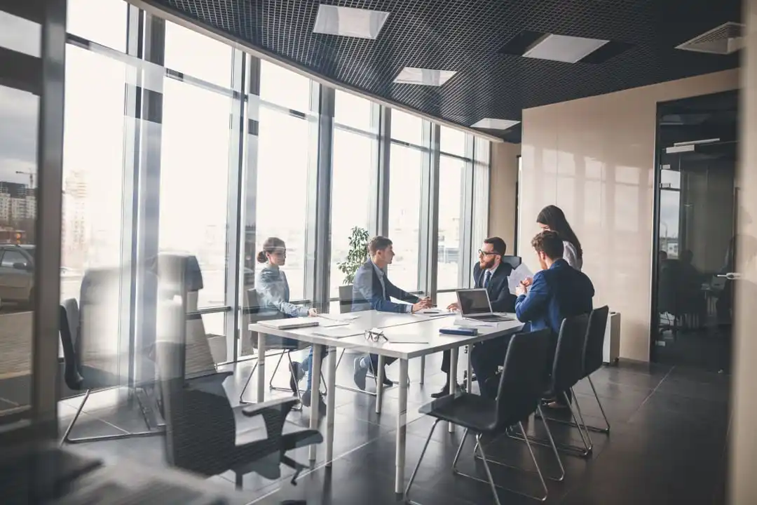 Business men and women sitting around conference room table talking