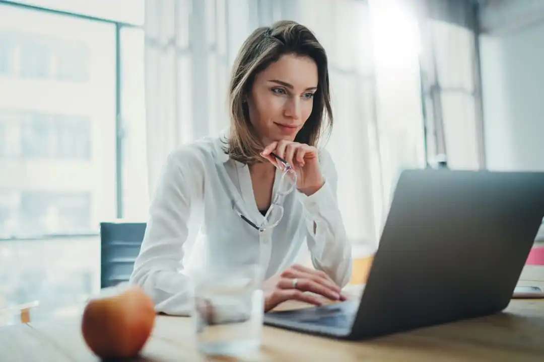 Woman staring and working on laptop at desk