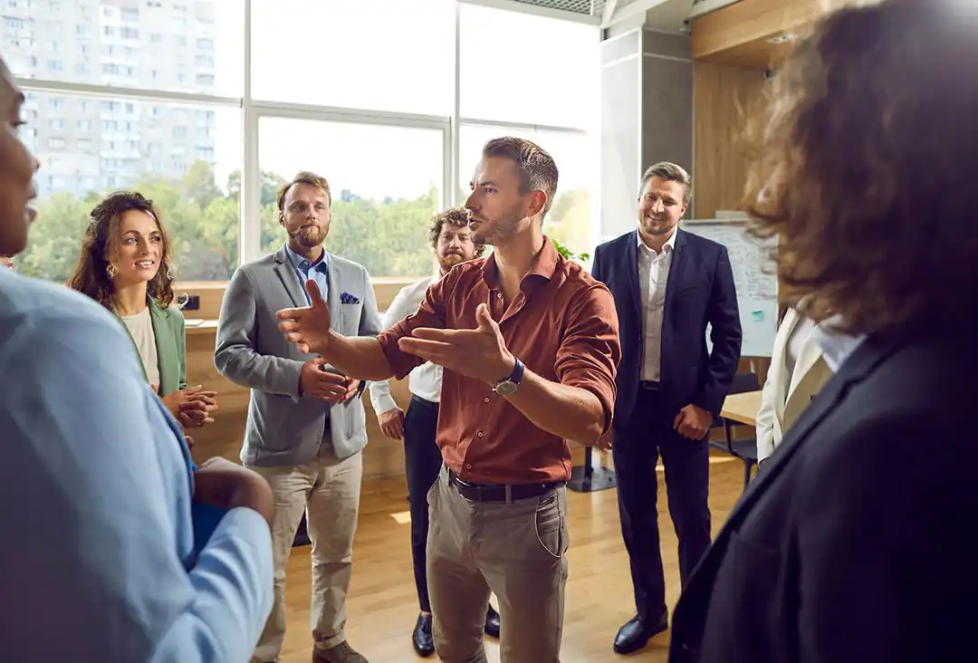 Guy in business casual talking to group of people in lobby area