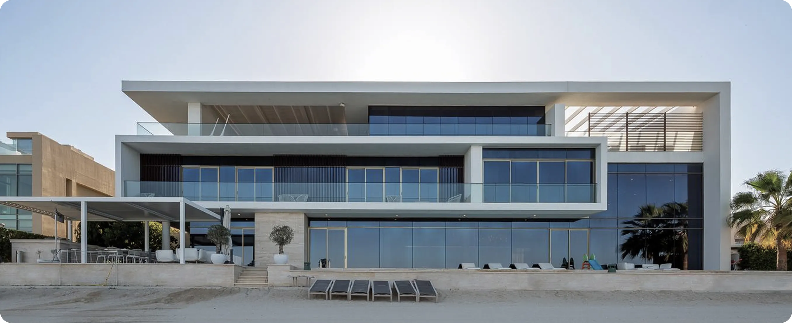 Luxury beachfront villa with expansive glass windows.