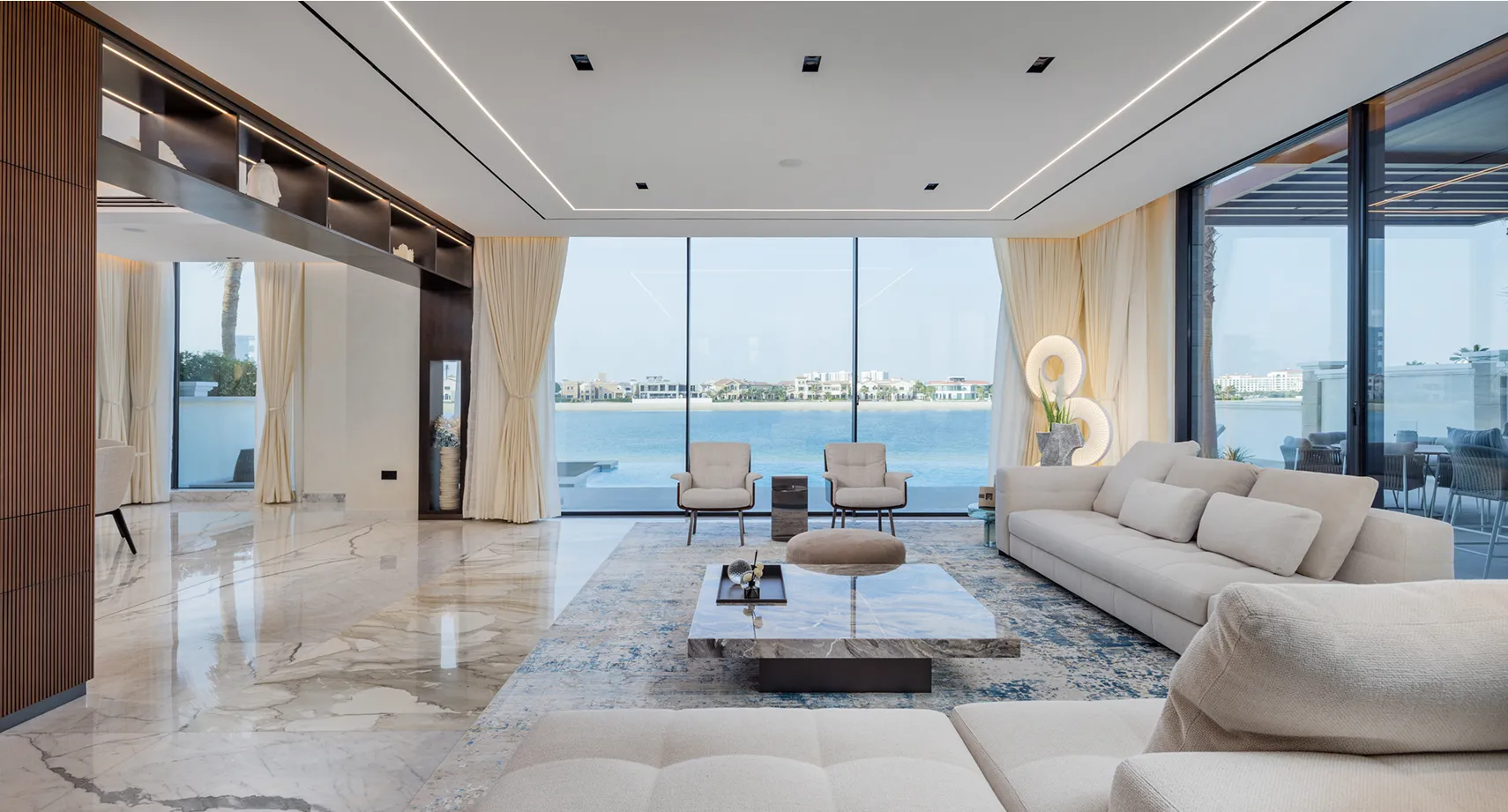 Living area in a palm villa with custom-designed modular sofas and floor-to-ceiling glass windows