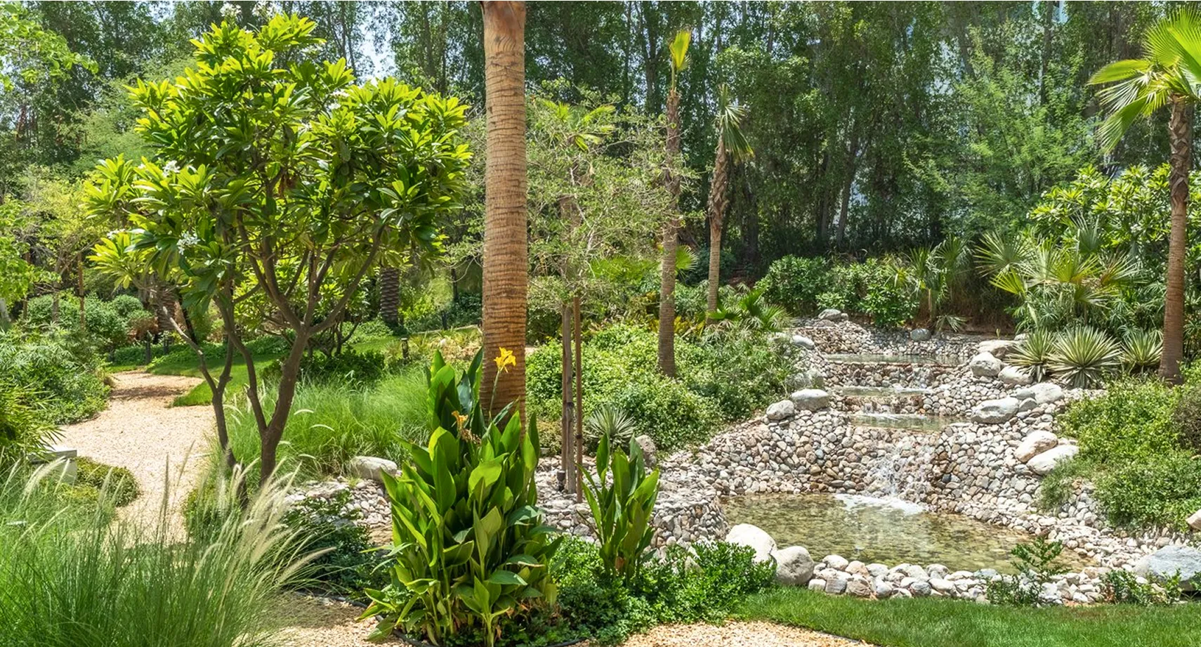 A lush green garden featuring a gravel path in a luxury villa