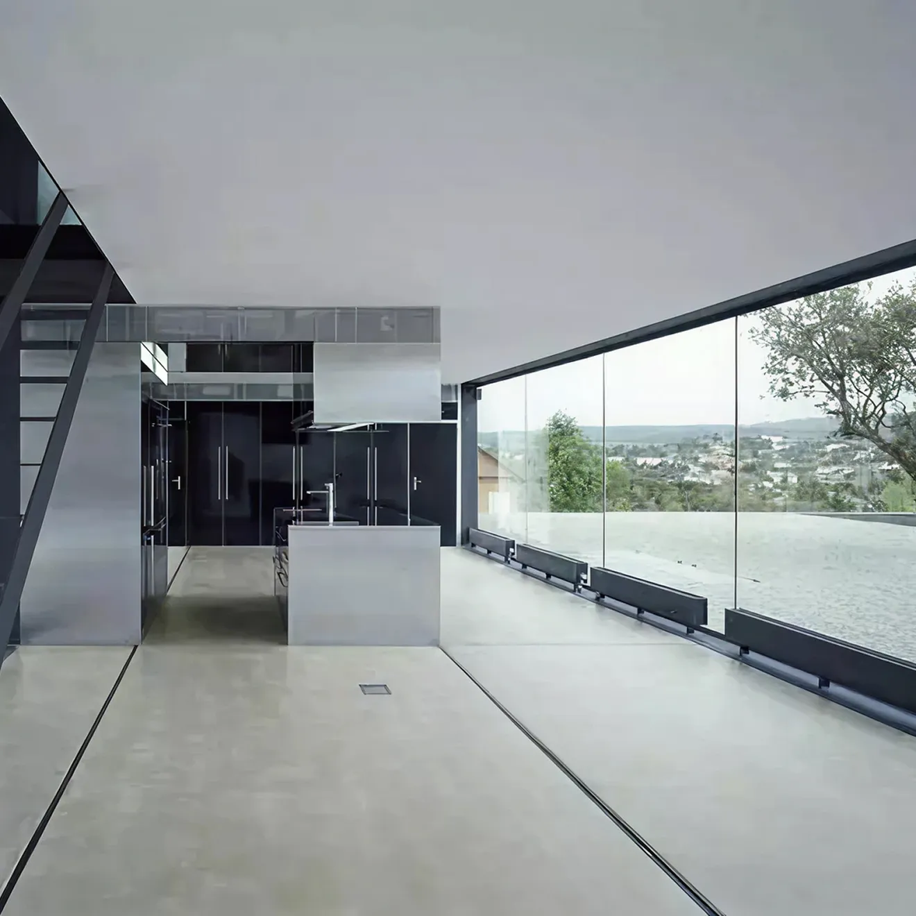 Modern minimalist interior with cabinetry and a metal staircase, featuring floor-to-ceiling bulletproof glass windows
