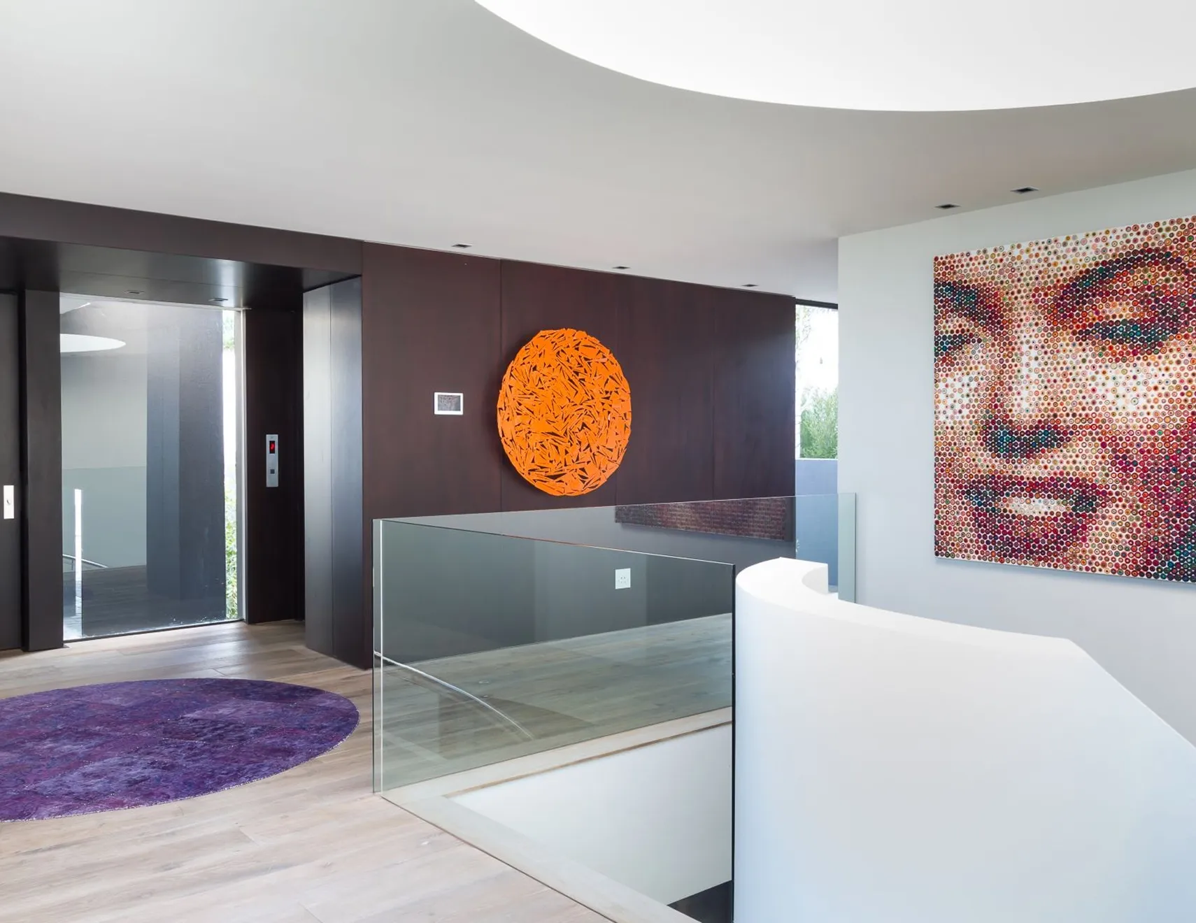 Modern villa interior design with light wood flooring, bold artwork, and a curved staircase