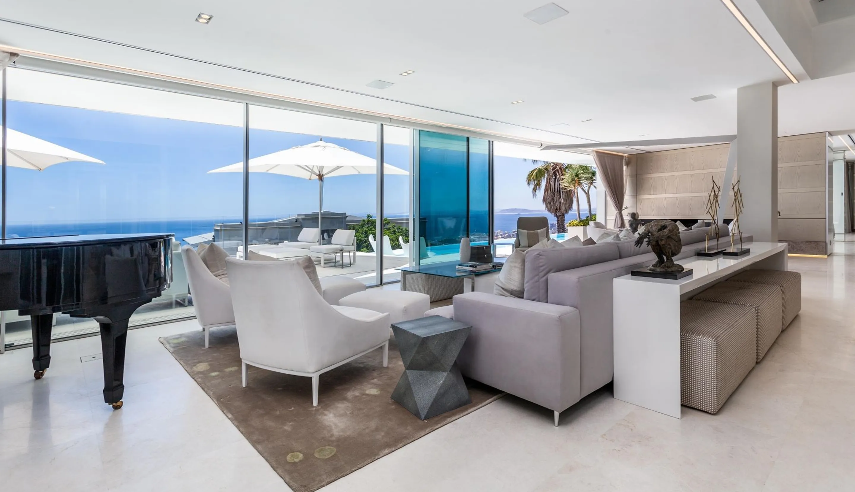 Living room with contemporary decor featuring floor-to-ceiling glass offering a panoramic view in a luxury villa