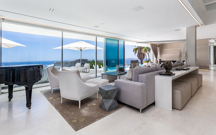 Living room with contemporary decor featuring floor-to-ceiling glass offering a panoramic view in a luxury villa