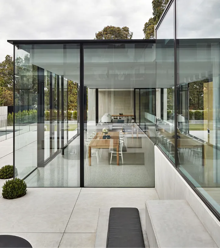 Minimalist house featuring transparent bulletproof glass walls that reveal a dining area