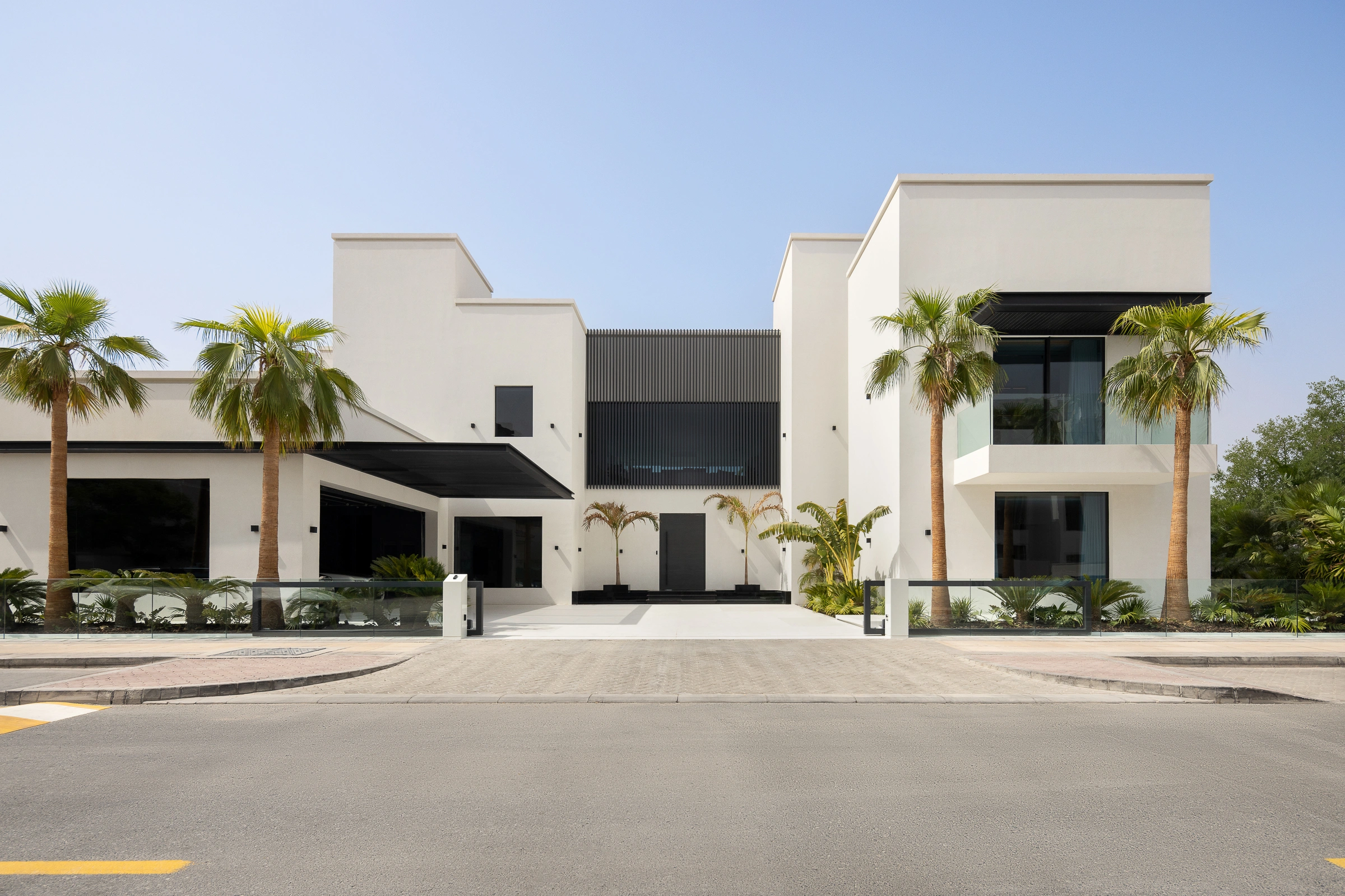 Minimalist office setup with a dark wood desk, a bookshelf, and ceiling track lights