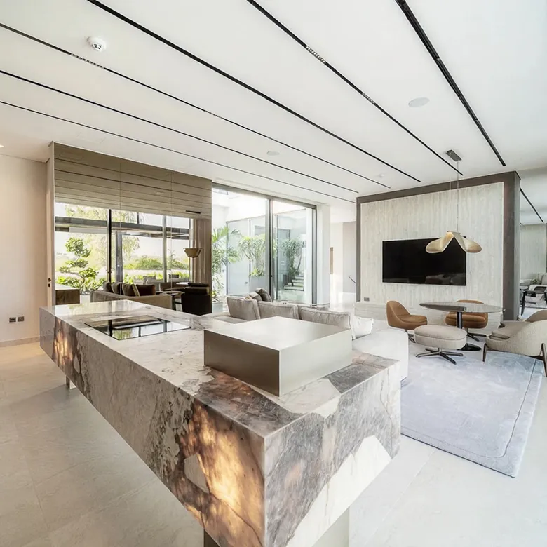 Contemporary villa interior design in Abu Dhabi with recessed lighting, marble island, and seamless indoor-outdoor flow.