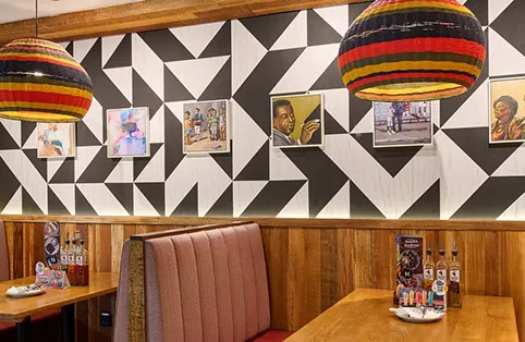 Dining space interior fit out featuring patterned wall, colorful hanging lights, and set tables in Dubai.