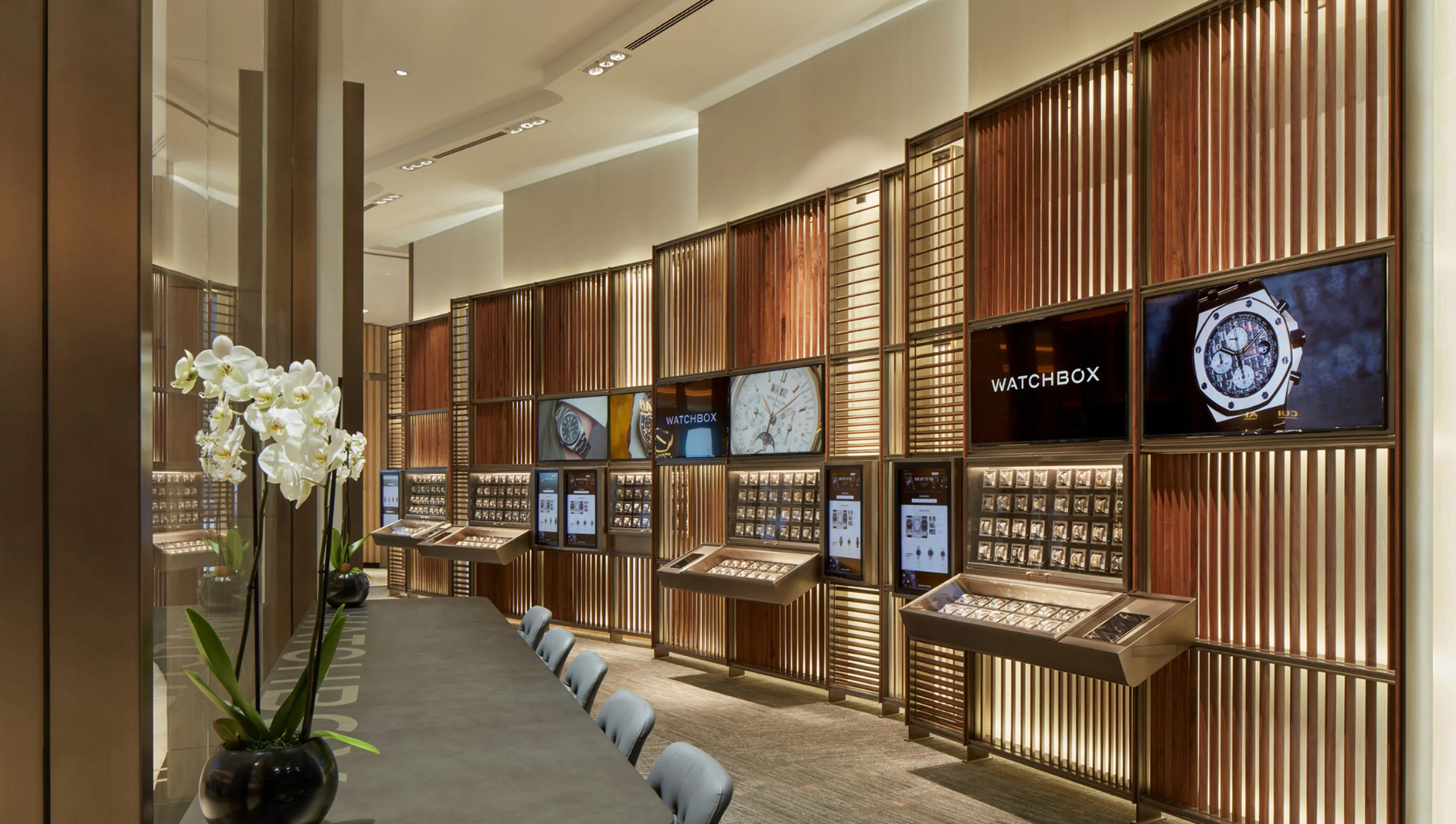 Luxury commercial interior design in the WatchBox showroom featuring wood displays, glass cases, and digital screens in Dubai.