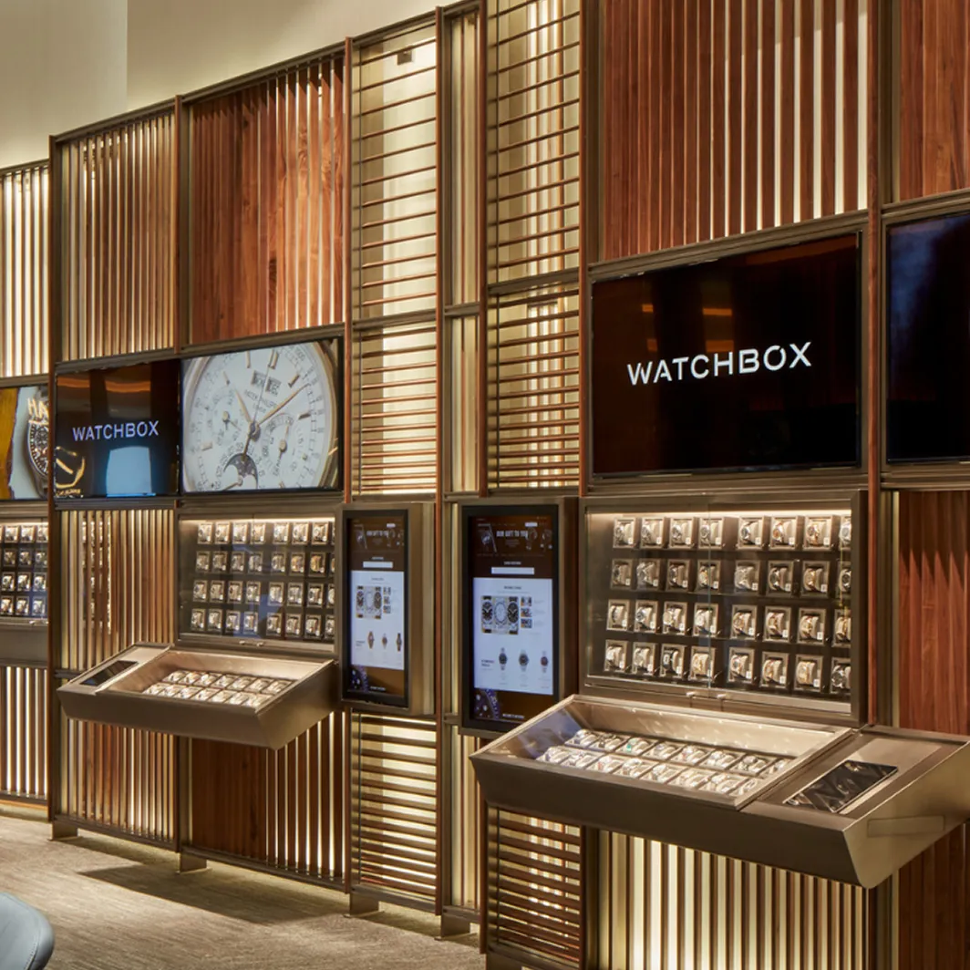 Modern luxury watch store interior with illuminated display cases and digital branding.