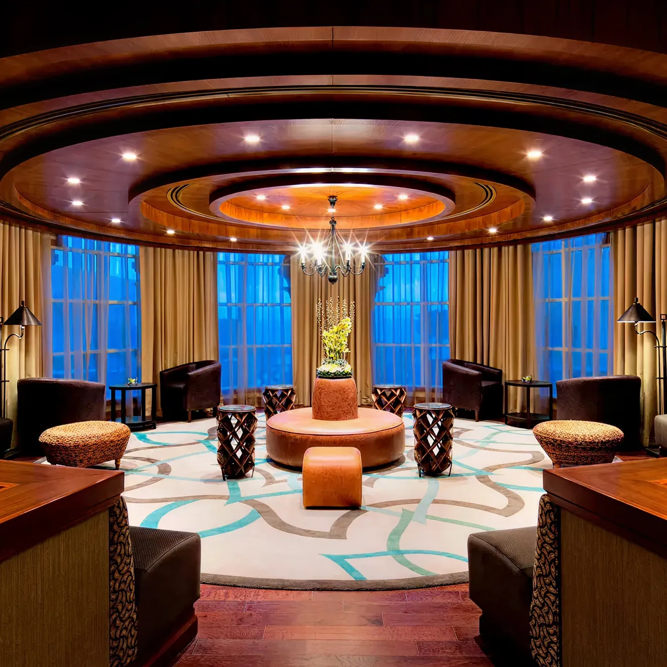 Lounge interior design highlighting dark wood floors, circular layout, and beige curtains.