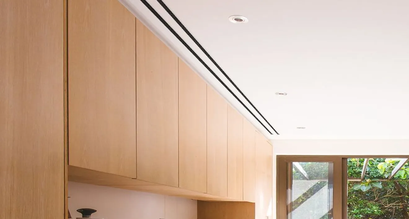 Modern kitchen interior featuring handleless light wood cabinets and custom ceiling design.